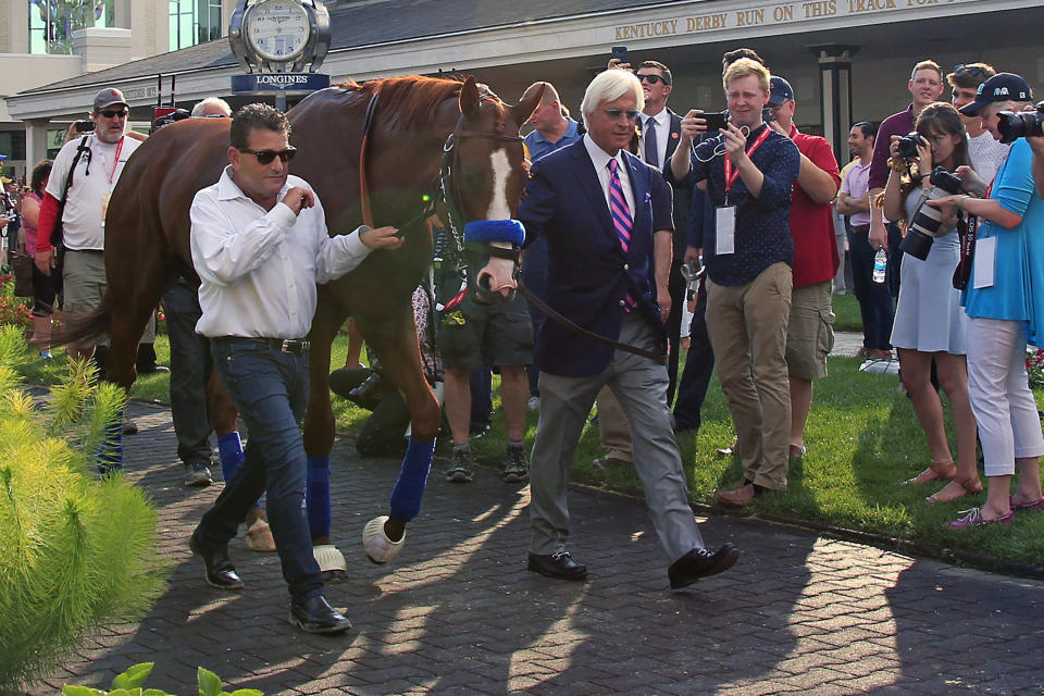 FILE - In this June 16, 2018, file photo, trainer Bob Baffert, right, and assistant Jimmy Barnes, left, lead Triple Crown winner Justify around the paddock at Churchill Downs in Louisville, Ky. Baffert is undefeated taking the Kentucky Derby winner to the Preakness, but for the first time in 20 years he’ll do so without assistant trainer Jimmy Barnes, who broke his right wrist in a paddock accident at Churchill Downs. (AP Photo/Garry Jones, File)