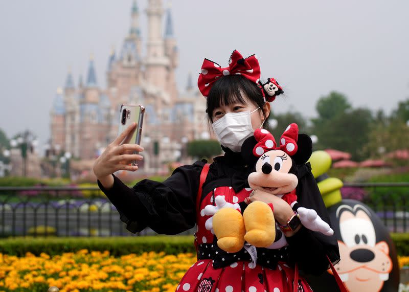 A visitor dressed as a Disney characters takes a selfie while wearing a protective face mask at Shanghai Disney Resort as the Shanghai Disneyland theme park reopens following a shutdown due to the coronavirus disease (COVID-19) outbreak, in Shanghai