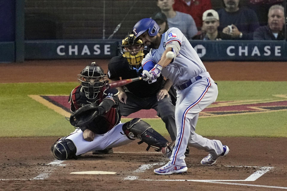 Texas Rangers' Marcus Semien, right, hits a two-run triple as Arizona Diamondbacks catcher Gabriel Moreno reaches for the pitch during the second inning in Game 4 of the baseball World Series Tuesday, Oct. 31, 2023, in Phoenix. (AP Photo/Ross D. Franklin)