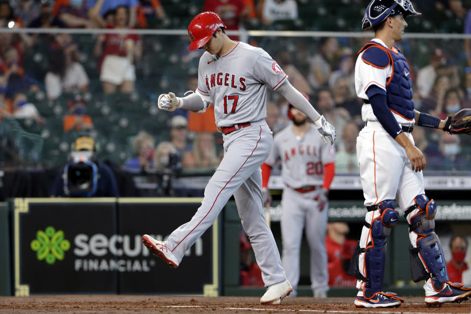 Los Angeles Angels designated hitter Shohei Ohtani (17) crosses the plate on his home run next to Houston Astros catcher Jason Castro, right, during the third inning of a baseball game Saturday, April 24, 2021, in Houston. (AP Photo/Michael Wyke)