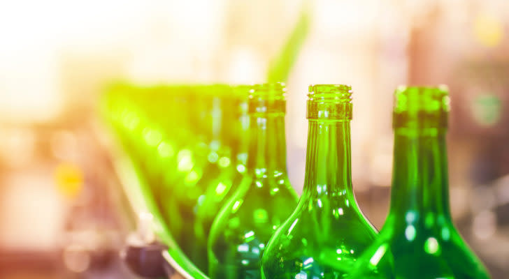 green beer bottles in a factory line, ready to be sealed. represents packaging companie