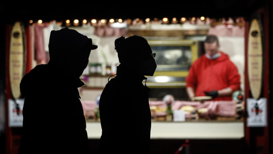 People with masks pass a Christmas booth in the city center of Duesseldorf, Germany, on Monday afternoon, Dec. 14, 2020. Chancellor Angela Merkel and the governors of Germany’s 16 states agreed Sunday to step up the country’s lockdown measures beginning Wednesday and running to Jan. 10 to stop the exponential rise of COVID-19 cases. (AP Photo/Martin Meissner)