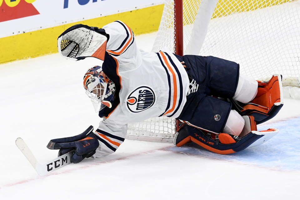 Edmonton Oilers goaltender Mike Smith (41) makes a dive for the puck during first-period NHL hockey game action against the Toronto Maple Leafs in Toronto, Saturday, March 27, 2021. (Frank Gunn/The Canadian Press via AP)