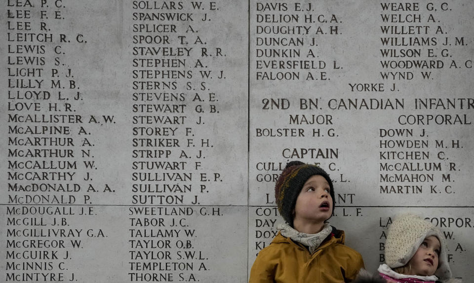 Two children look up at a wall of the missing during an Armistice Day ceremony at the Menin Gate Memorial to the Missing in Ypres, Belgium, Thursday, Nov. 11, 2021. (AP Photo/Virginia Mayo)