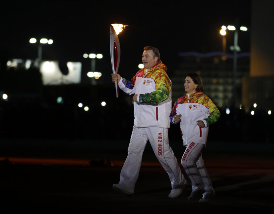 Irina Rodnina and Vladislav Tretiak run before lighting the Olympic cauldron during the opening ceremony of the 2014 Winter Olympics in Sochi, Russia, Friday, Feb. 7, 2014. (AP Photo/Matt Slocum, Pool)