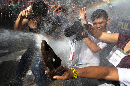 Protesters are hit by a water cannon as they try to march towards the U.S. embassy during a rally against U.S. President Donald Trump's visit, in Manila, Philippines November 12, 2017. REUTERS/Athit Perawongmetha