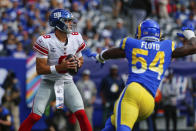 New York Giants quarterback Daniel Jones, left, looks to throw under pressure during the first half of an NFL football game against the Los Angeles Rams, Sunday, Oct. 17, 2021, in East Rutherford, N.J. (AP Photo/John Munson)