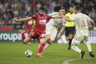 Brest's Pierre Lees-Melou, left, attempts a shot on goal during a French League One soccer match between Lyon and Brest at the Groupama stadium, outside Lyon, France, Sunday, April 14, 2024. (AP Photo/Laurent Cipriani)