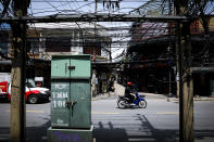 <p>A man rides a scooter past a clutter of cables along a street in Bangkok, Thailand, May 18, 2017. Talks of placing existing overhead power lines and cables underground are underway. (Photo: Diego Azubel/EPA) </p>