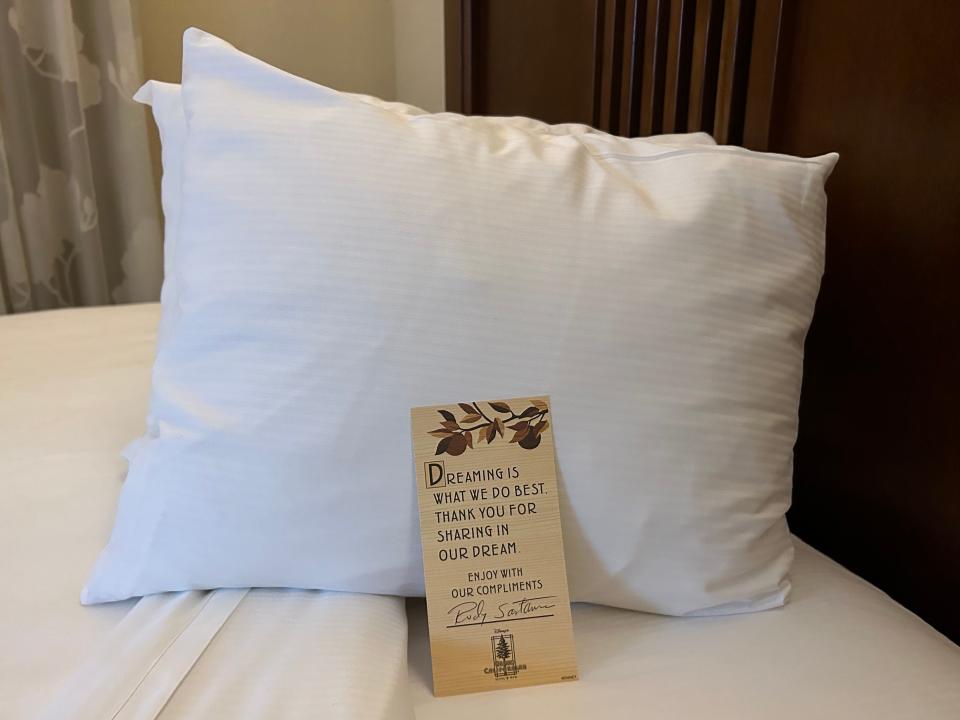 A card placed on a pillow that reads, "Dreaming is what we do best. Thank you for sharing in our dream. Enjoy with our compliments."