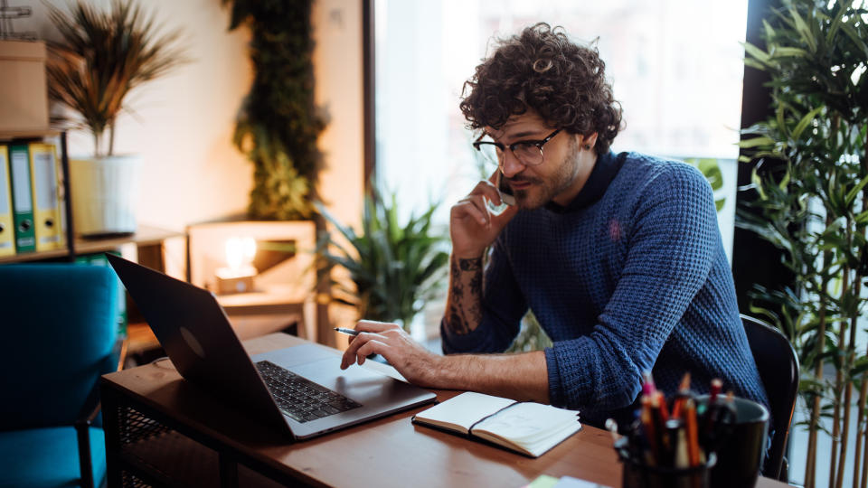 Young man talking on the phone in his home office.