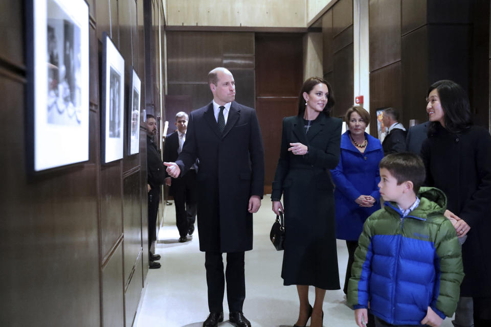 Boston Mayor Michelle Wu, right, and her family show photographs of Queen Elizabeth II's visit in 1976, during the visit of Britain's Prince William and Kate, Princess of Wales, to Boston City Hall on Wednesday, Nov. 30, 2022, in Boston. The Prince and Princess of Wales are making their first overseas trip since the death of Queen Elizabeth II in September. (Nancy Lane/The Boston Herald via AP, Pool)