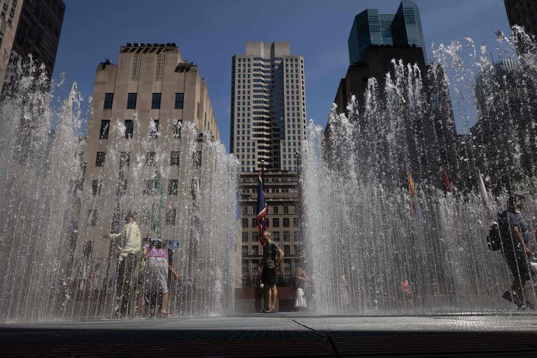 La gente juega en la escultura a base de agua del artista Jeppe Hein titulada &quot;Changing Spaces&quot; en el Rockefeller Center Plaza en Nueva York 