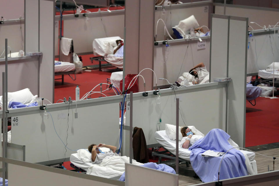 FILE - In this Thursday, April 2, 2020 file photo, patients lie in beds at a temporary field hospital in the Ifema convention center in Madrid, Spain. As coronavirus deaths climbed, engineers laid 7 kilometers (4 miles) of tubing in less than a week to give 1,500 beds in the impromptu facility a direct supply of pure oxygen. (AP Photo/Manu Fernandez)
