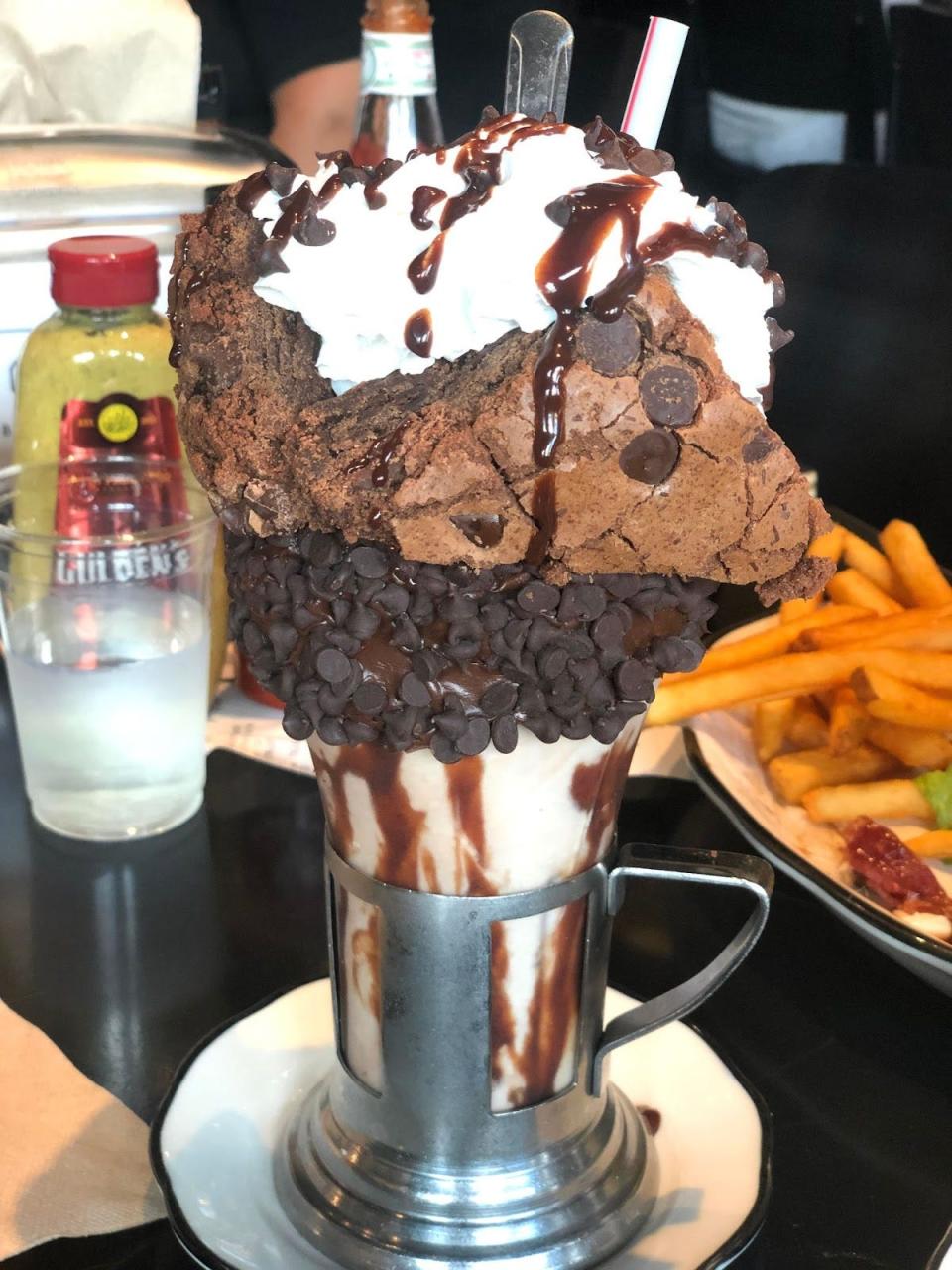 Large milkshake with vanilla ice cream, brownies, chocolate chips, and chocolate sauce drizzled on top