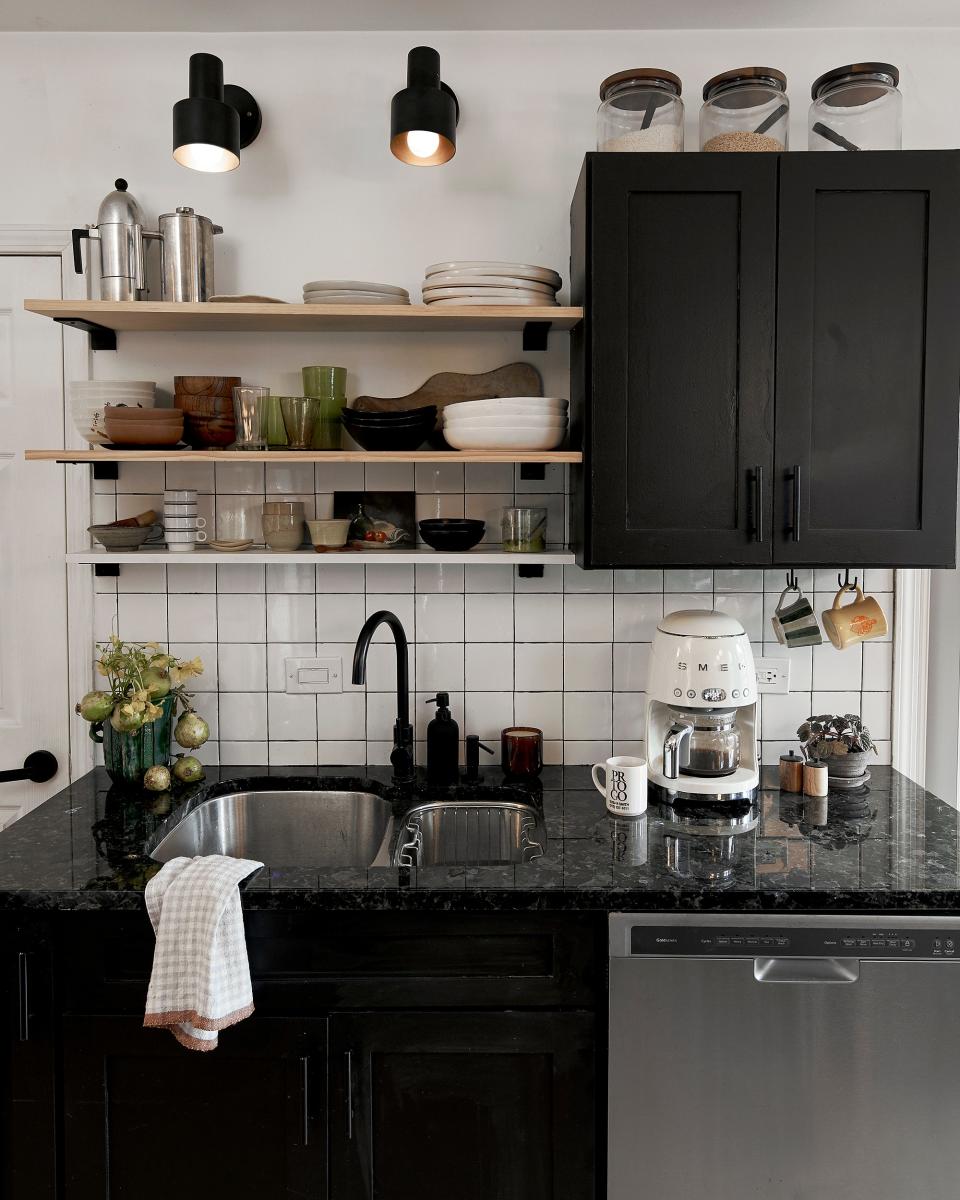 Paige Wassel painted the cherry cabinets matte black, installed open shelving, and added a new backsplash in the kitchen. “I removed the boob light on the ceiling and installed two round pendant lights above the counter. And of course, the new wood flooring. The old tile was depressing.”