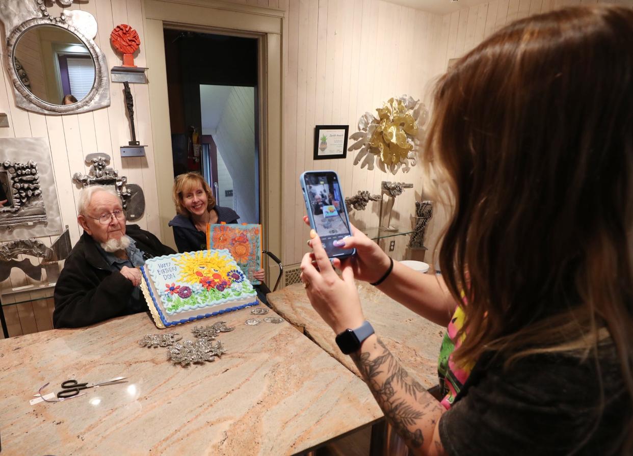 Artists Don Drumm and Leandra Drumm, his daughter, pose with an early birthday cake as Makaila Stroud, marketing and advertising manager at Don Drumm Studios & Gallery , takes their picture. Don's birthday is April 11, three days after the eclipse.