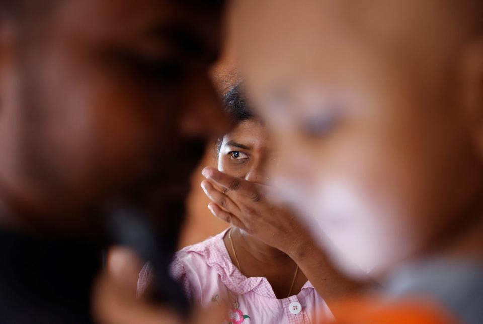 Sathiyaraj Silaksana cries as her husband Kesakarasa Sathiyaraj hugs their son, S Saksan (Reuters)