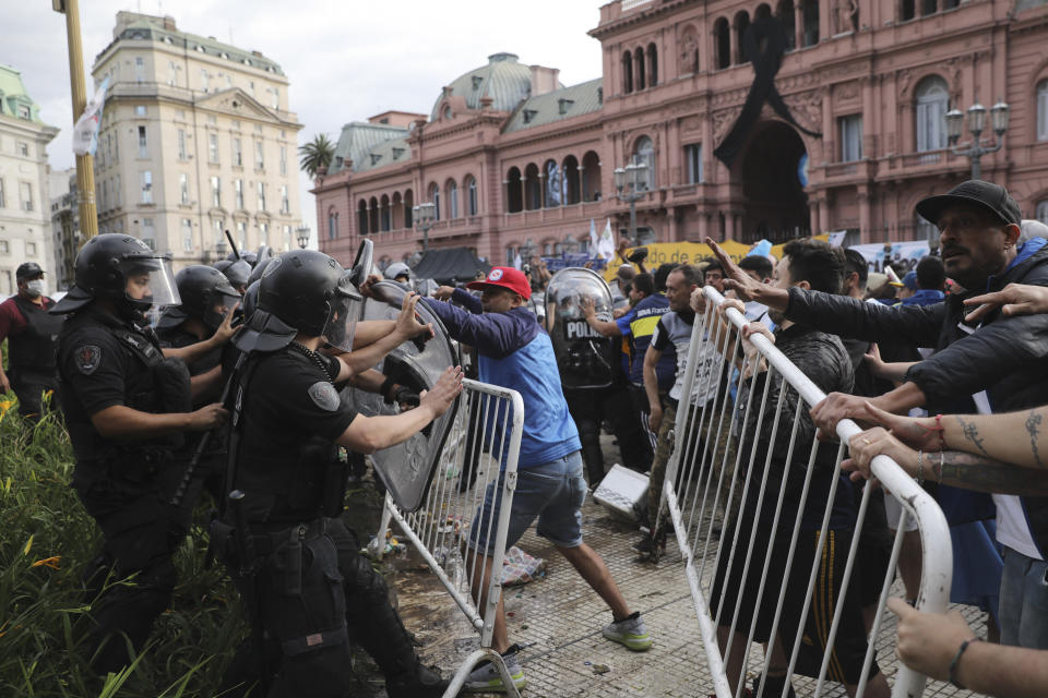 Soccer fans waiting to see Diego Maradona lying in state clash with police outside the presidential palace in Buenos Aires, Argentina, Thursday, Nov. 26, 2020. The Argentine soccer great who led his country to the 1986 World Cup title died Wednesday at the age of 60. (AP Photo/Rodrigo Abd)