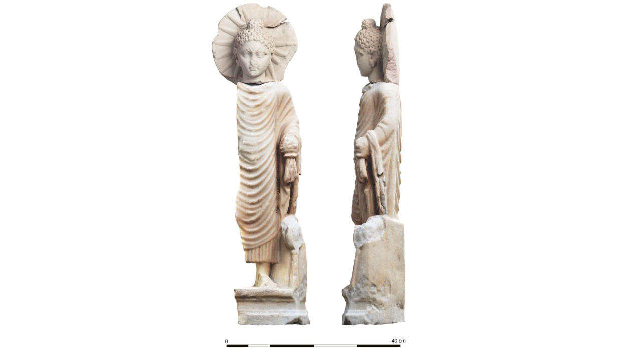 Two views of a broken standing Buddha statue carved out of white stone. One view is the profile. The other is a frontal image, showing Buddha dressed in robes with halo-like circle behind his head. 