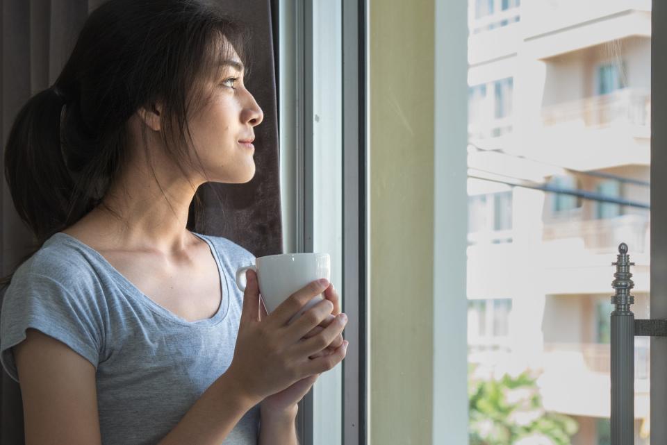 woman standing staring out window