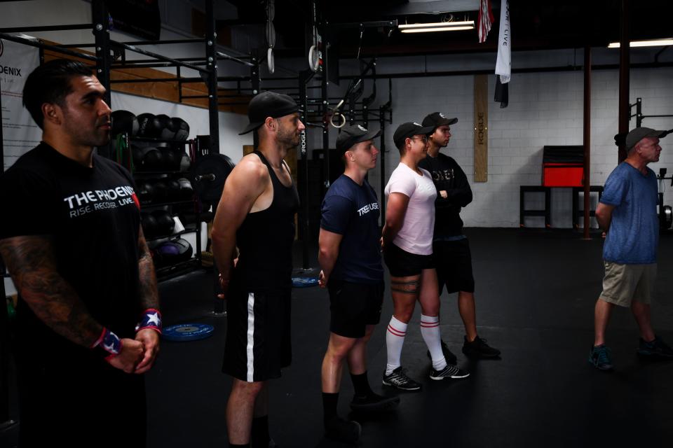 Members of The Phoenix sober active community listen to instructions before their cross-fit workout.