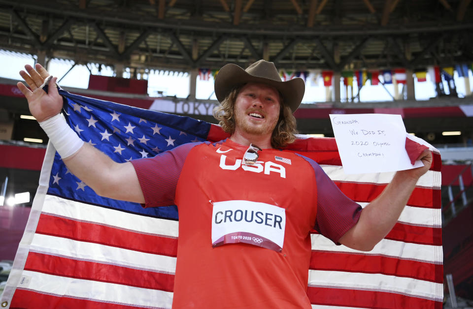 Ryan Crouser, of United States, holds a sign while celebrating winning the gold medal in the final of the men's shot put at the 2020 Summer Olympics, Thursday, Aug. 5, 2021, in Tokyo, Japan. (Matthias Hangst/Pool Photo via AP)