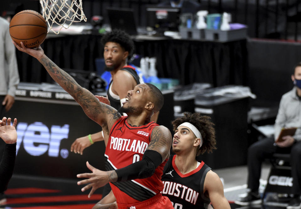 Portland Trail Blazers guard Damian Lillard drives to the basket past Houston Rockets guard Brodric Thomas during the second half of an NBA basketball game in Portland, Ore., Saturday, Dec. 26, 2020. The Blazers won 128-126 in overtime. (AP Photo/Steve Dykes)
