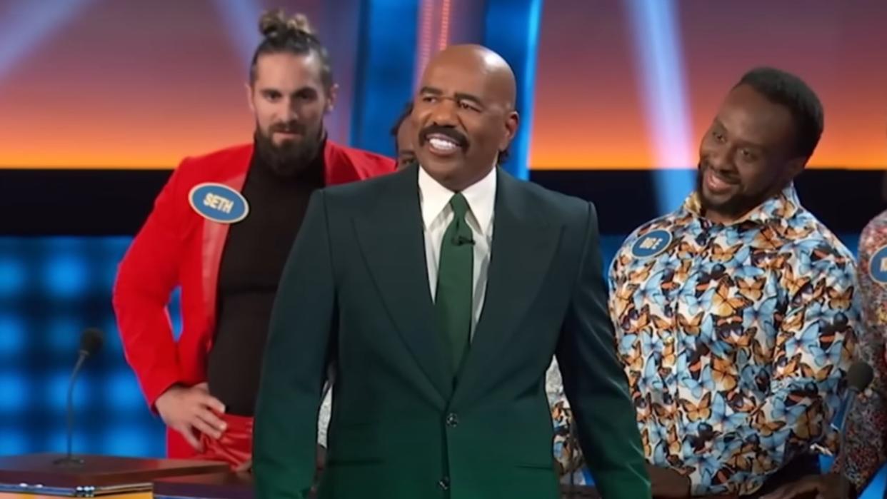  Steve Harvey smiling with Seth Rollins, Big E, and Kofi on Celebrity Family Feud 