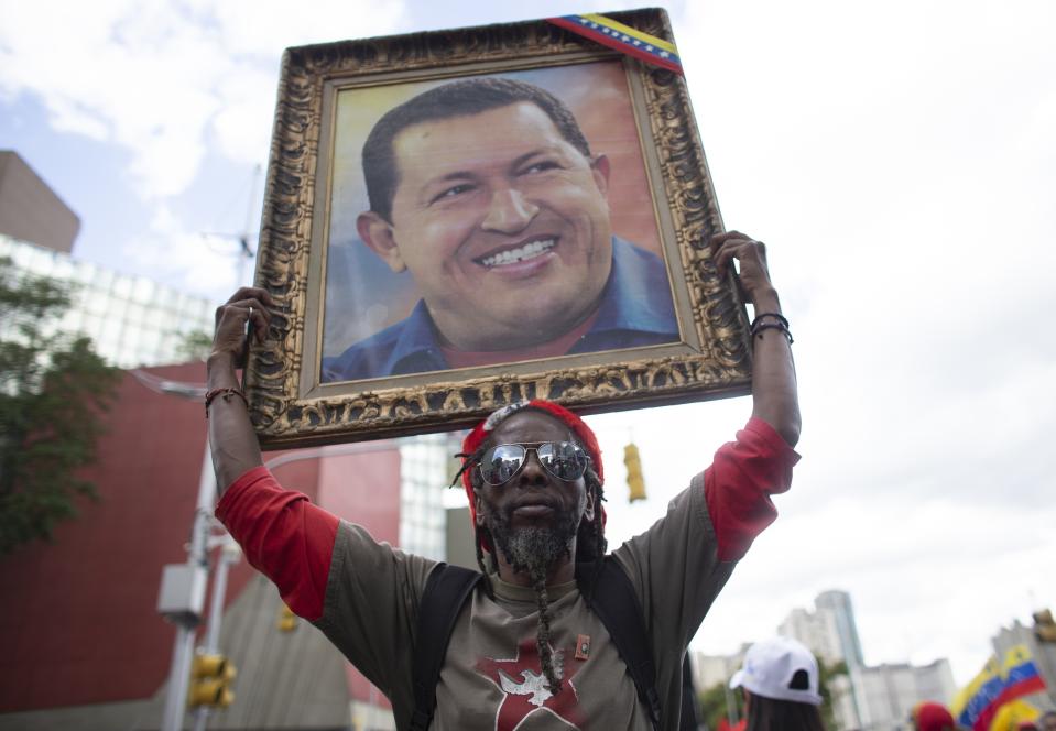 A supporter of President Nicolas Maduro holds up a painting of late President Hugo Chavez during an anti-imperialist rally in Caracas, Venezuela, Saturday, August 31, 2019. Venezuelan officials say they have proof of paramilitary training camps operating in neighboring Colombia where groups are purportedly plotting attacks to undermine President Nicolás Maduro. (AP Photo/Ariana Cubillos)