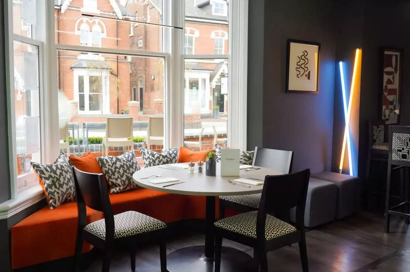 Chapter in Edgbaston - picture shows a dining table inside with an orange sofa and artwork on the walls