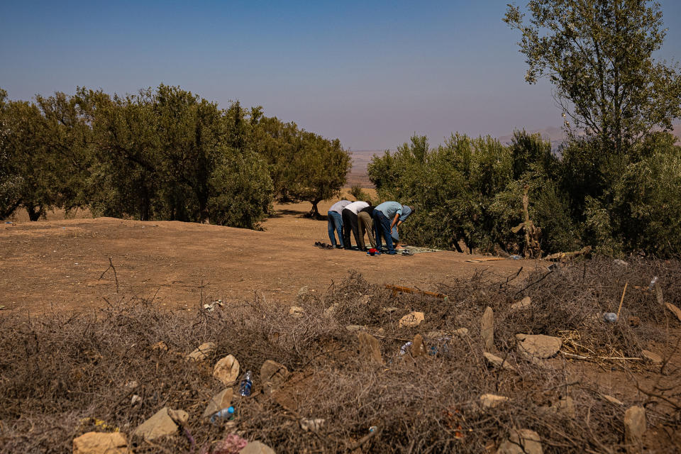 People pray behind graves in Taheghaghte, Morocco, on Sept. 11, 2023. (Bill O'Reilly / NBC News)