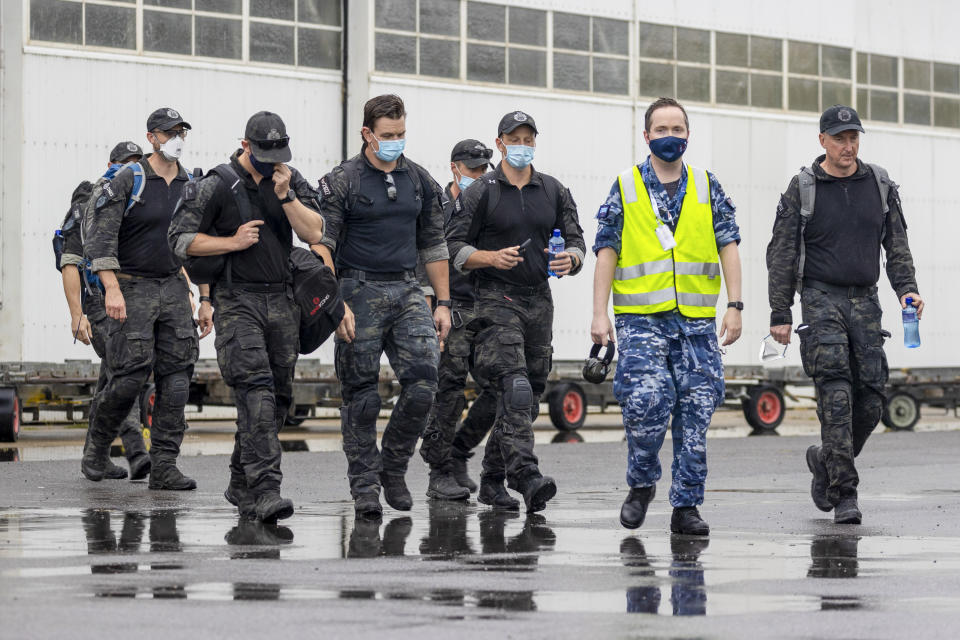 In this photo released by Australian Department of Defense, Australian Federal Police Special Operations members are escorted across the tarmac to a Royal Australian Air Force jet for their flight to the Solomon Islands, in Canberra, Australia, Thursday, Nov. 25, 2021. Australia says it is sending police, troops and diplomats to the Solomon Islands to help after anti-government demonstrators defied lockdown orders and took to the streets for a second day in violent protests. (LACW Jacqueline Forrester/Australian Department of Defense via AP)