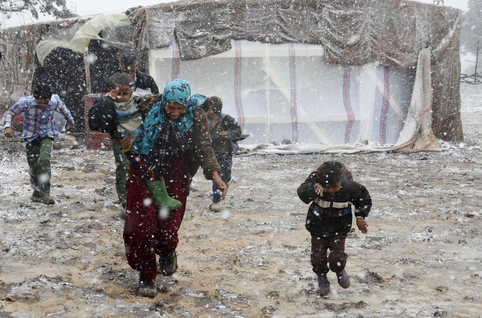 Syrian refugees run for cover from snow during a winter storm in Zahle town, in the Bekaa Valley December 11, 2013. The worst of winter is yet to come for 2.2 million refugees living outside Syria and millions more displaced inside the country. A storm named Alexa is sweeping across Syria and Lebanon, bringing with it high winds and freezing temperatures - and marking the beginning of the third winter since the Syrian conflict began in March 2011. In the tented settlement a few kilometres (miles) from the border in Lebanon's Bekaa Valley, more than 1,000 people live in rudimentary shelters. REUTERS/Mohamed Azakir (LEBANON - Tags: POLITICS CIVIL UNREST CONFLICT SOCIETY IMMIGRATION ENVIRONMENT ENERGY TPX IMAGES OF THE DAY)