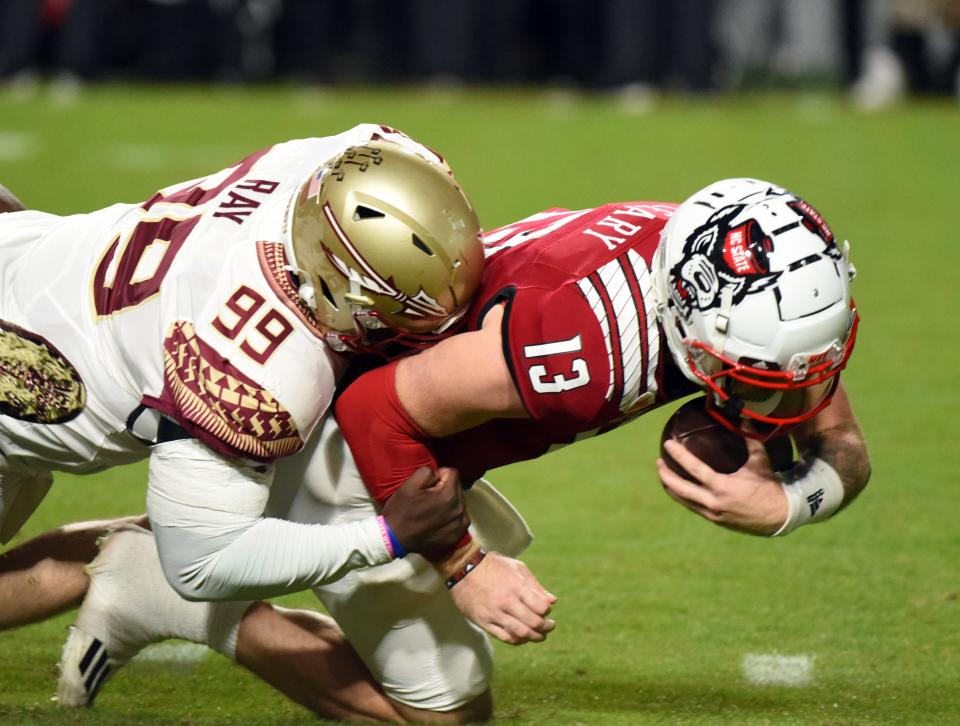 Oct 8, 2022; Raleigh, North Carolina, USA; North Carolina State Wolfpack quarterback Devin Leary (13) is sacked by Florida State Seminoles defensive tackle Malcolm Ray (99) during the first half at Carter-Finley Stadium. Mandatory Credit: Rob Kinnan-USA TODAY Sports