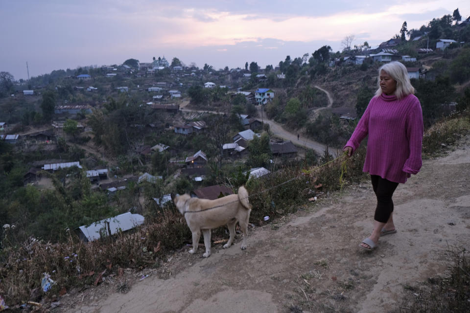 A woman walks her dog in Shangshak village, in the northeastern state of Manipur, India, Sunday, March 22, 2020. (AP Photo/Yirmiyan Arthur)