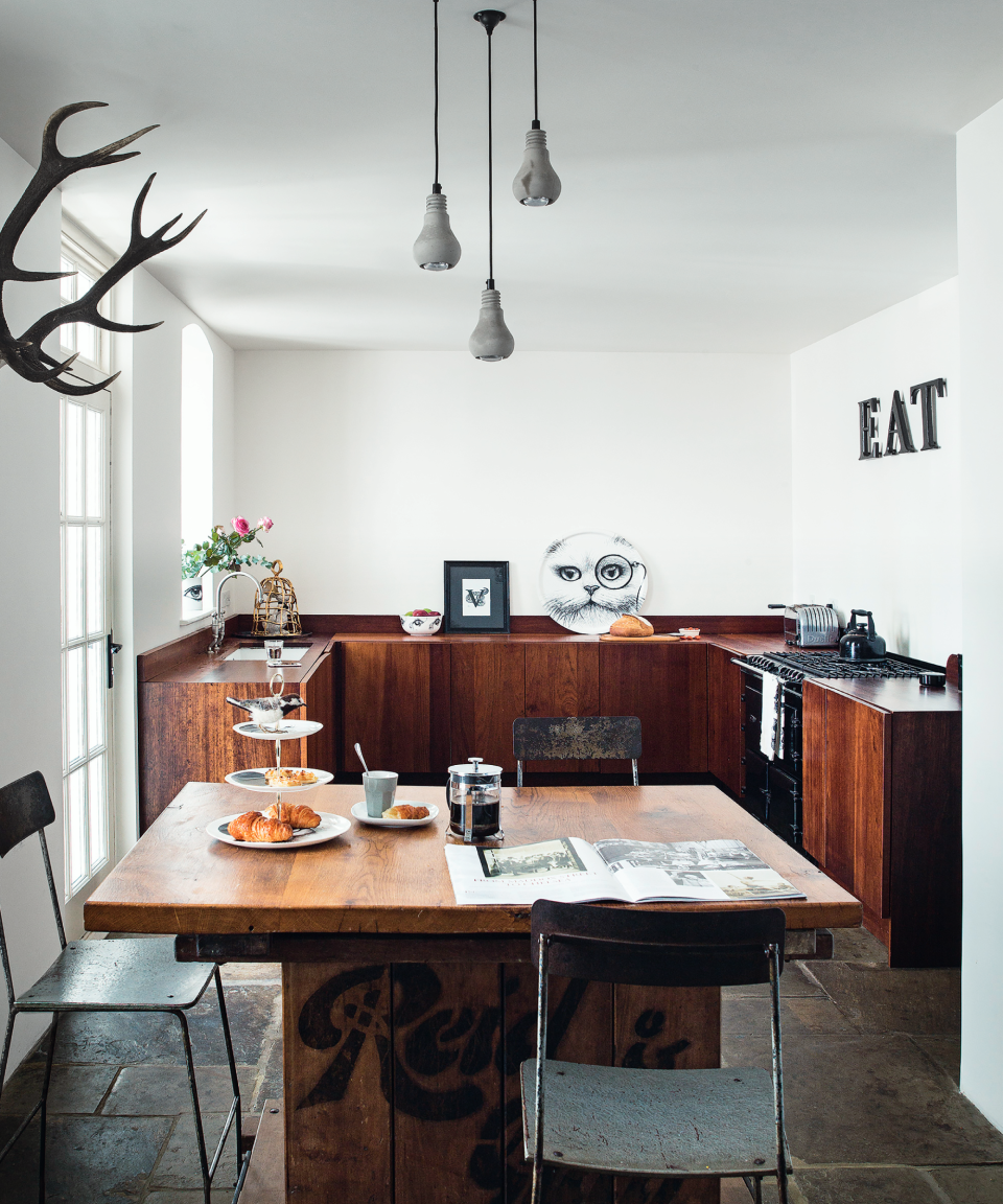 An example of small kitchen layout ideas showing a U-shaped kitchen and dining area in dark wood with white walls