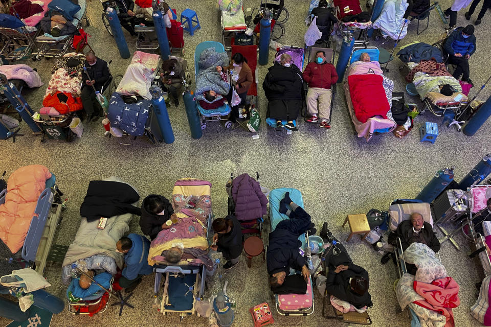 People look after their elderly relatives lying on stretchers and receiving intravenous drips while using ventilators at the Changhai Hospital hall in Shanghai, China, Tuesday, Jan. 3, 2023. As COVID-19 rips through China, other countries and the World Health Organization are calling on its government to share more comprehensive data on the outbreak. Some even say many of the reported numbers are meaningless. (Chinatopix Via AP)