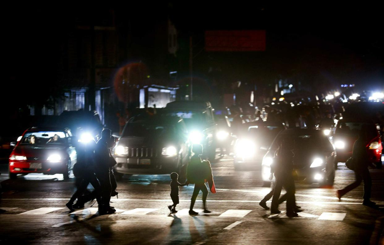 Residentes cruzan una calle en la oscuridad tras un apagón en Caracas, Venezuela, el jueves 7 de marzo de 2019. (AP Foto/Eduardo Verdugo)