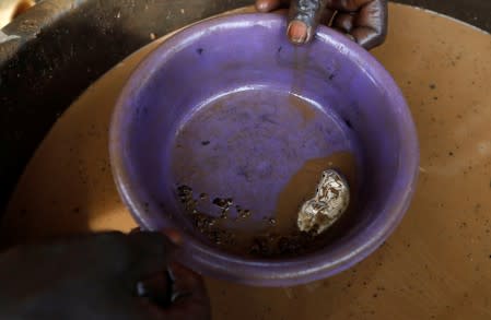 An informal gold miner adds mercury to panned material to suck the gold out of the dirt at the site of Nsuaem-Top in Ghana