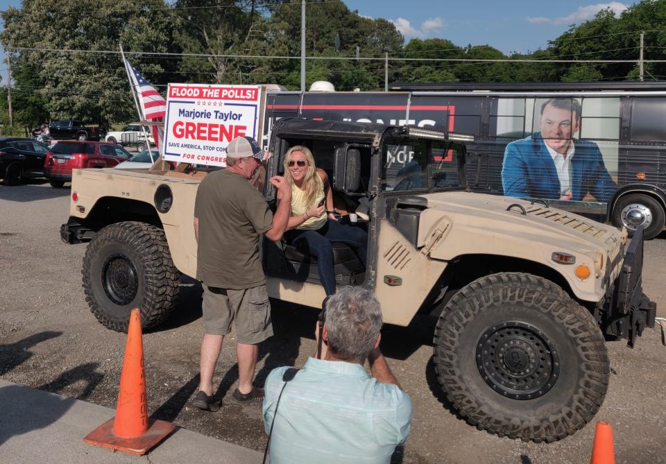 Republican Rep. Marjorie Taylor Greene of Georgia, seated in the passenger seat of a doorless Humvee vehicle, chats with Crazy Acres Bar & Grill owner Jerry Stroup after pulling into the parking lot for a Bikers for Trump rally on May 20, in Plainville, Georgia.