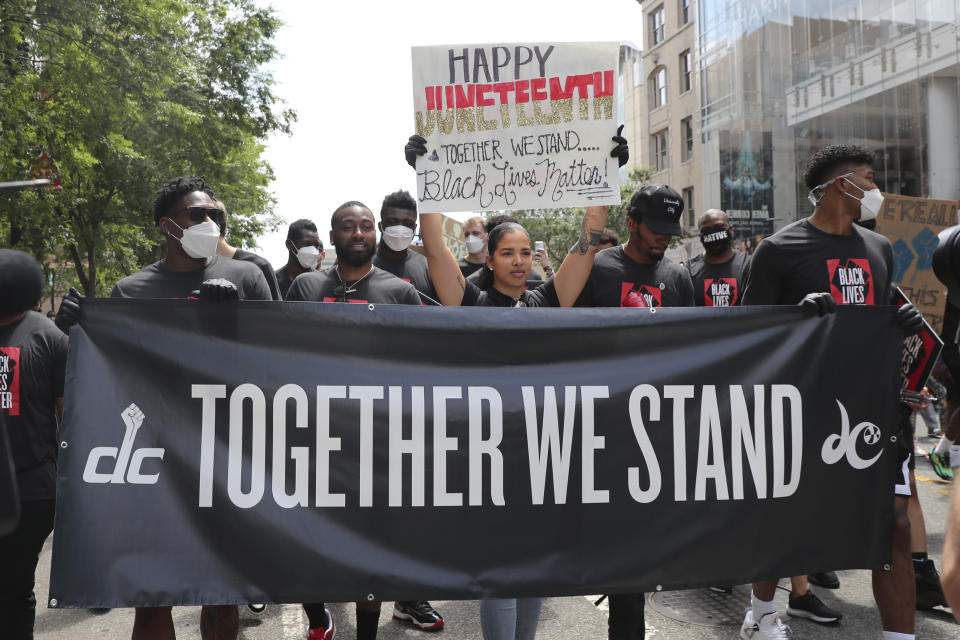 The Washington Mystics' Natasha Cloud is joined by the Washington Wizards' John Wall and Bradley Beal for a Black Lives Matter march down the streets of D.C. to the MLK Memorial. They are holding a black sign that says 