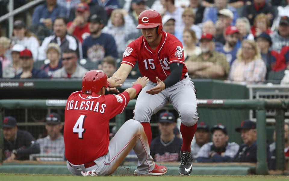 Cincinnati Reds' Nick Senzel (15) helps Jose Iglesias (4) up off the ground after they scored runs against the Cleveland Indians during the second inning of a spring training baseball game Monday, March 11, 2019, in Goodyear, Ariz. (AP Photo/Ross D. Franklin)