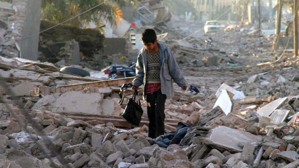 Un niño camina entre los escombros tras el terremoto de 2003 en Bam, Irán.