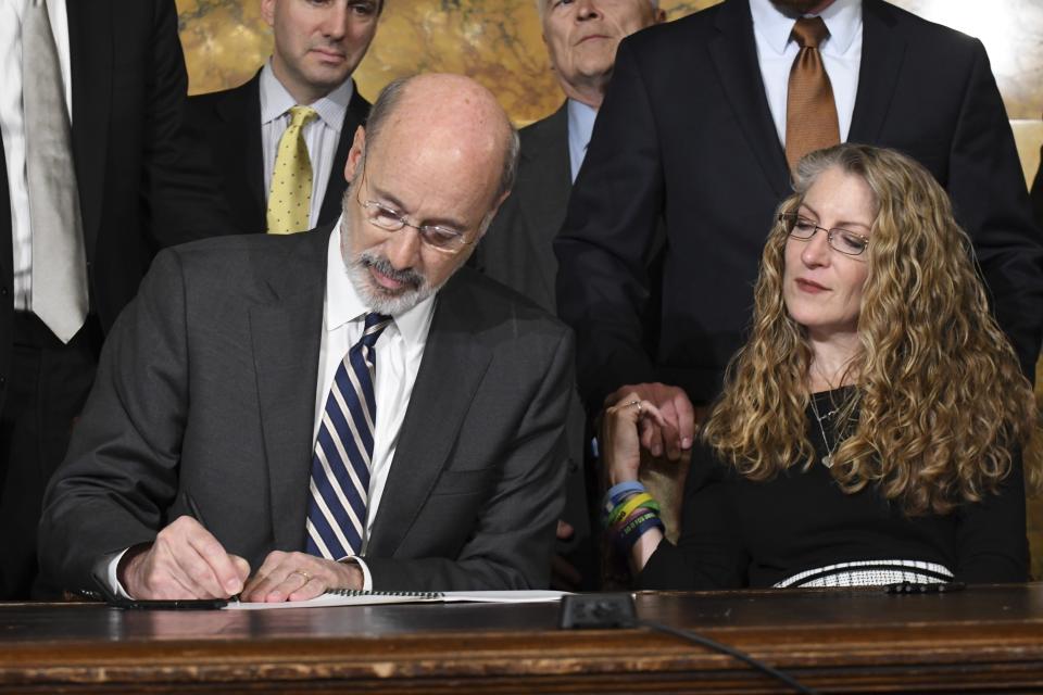 Pennsylvania Gov. Tom Wolf of Pennsylvania signs anti-hazing legislation inspired by Penn State student Tim Piazza who died after a night of drinking in a fraternity house, Friday, Oct. 19, 2018 in Harrisburg, Pa. Sitting next to Wolf is Evelyn Piazza, the mother of Tim Piazza. (AP Photo/Marc Levy)