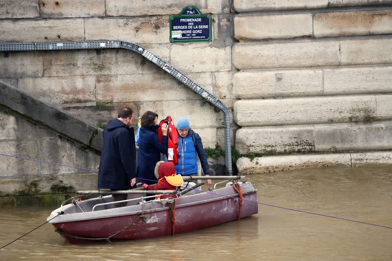 The members of a family get off a small boat on the flooded river-side of river Seine as water levels are expected to hit 4.3 metres today in Paris