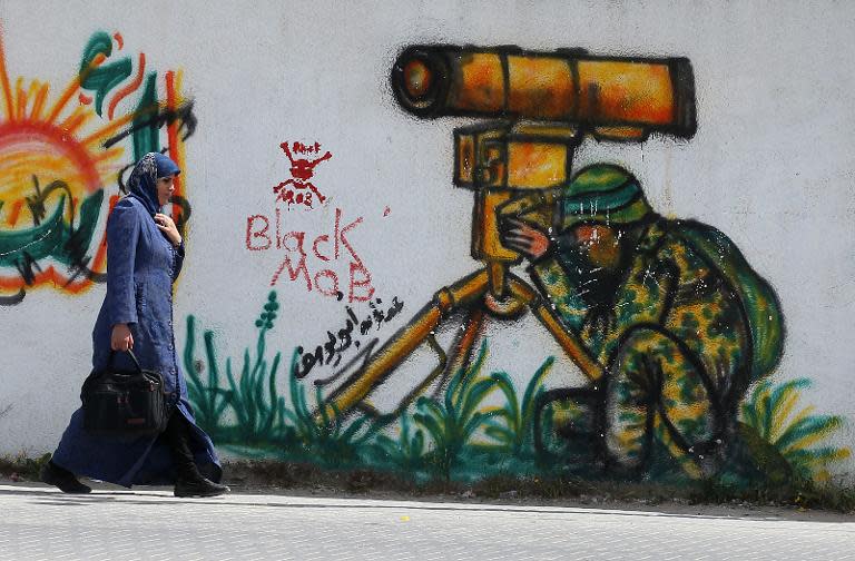 A Palestinian woman walks past a mural in the east of Khan Yunis, in the southern Gaza Strip, on March 26, 2015