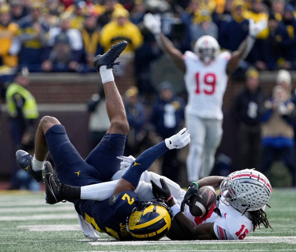Ohio State receiver Marvin Harrison Jr. is tackled by Michigan cornerback Will Johnson after a long reception.