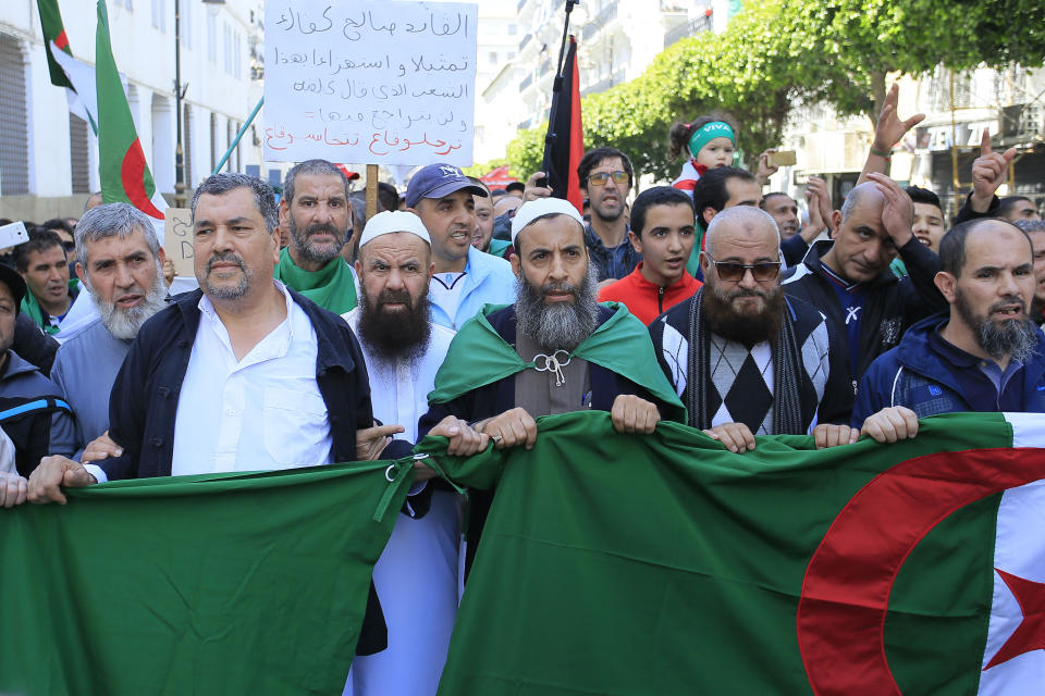 Demonstrators march with the Algerian flag during a protest in Algiers, Friday, April 26, 2019. Algerians are massing for a 10th week of protests against their country's ruling class, calling for the ex-president's brother to be put on trial. (AP Photo/Anis Belghoul)