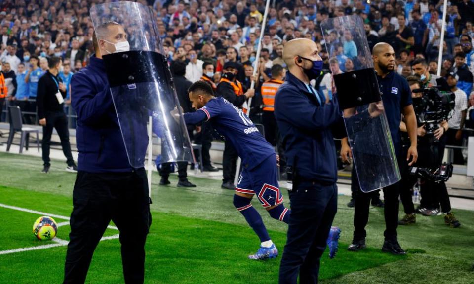 Security staff hold riot shields to protect Paris Saint-Germain’s Neymar from objects thrown by Marseille supporters